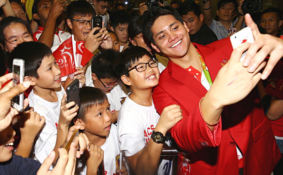 Singaporean swimmer Joseph Schooling right poses for a selfie as he arrives at Singapore Changi Airport