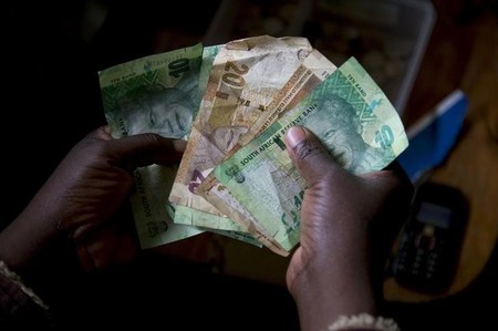 A shopkeeper counts out change above her cash box at her shop in Hillcrest west of Durban