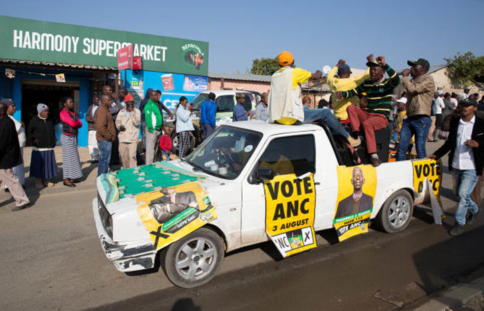 An ANC party vehicle appeals for votes as locals are seen outside a voting station during the local government elections in Diepsloot township north of Johannesburg South Africa on Wednesday. — Reuters