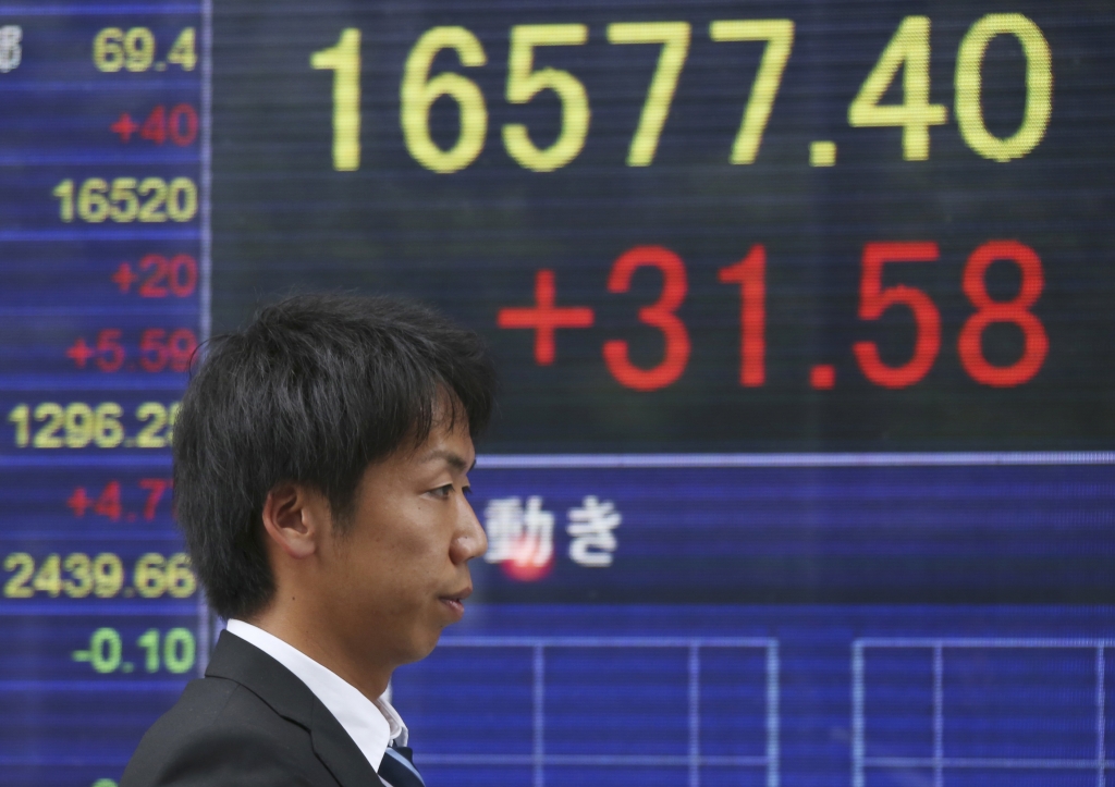 Japan Financial Markets A man walks by an electronic stock board of a securities firm in Tokyo Monday Aug. 22 2016. Asian stocks meandered on Monday as investors looked ahead to the Fed's meeting in Jackson Hole Wyoming for clues on timing for