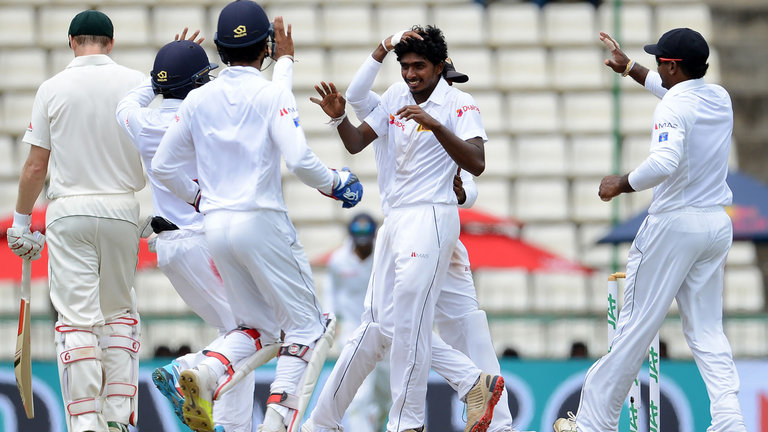 Sri Lankan spinner Lakshan Sandakan is congratulated by team-mates after taking his first Test wicket