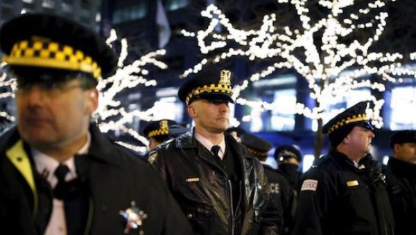 Police officers watch protesters during a demonstration in reaction to the fatal shooting of Laquan Mc Donald in Chicago Illinois