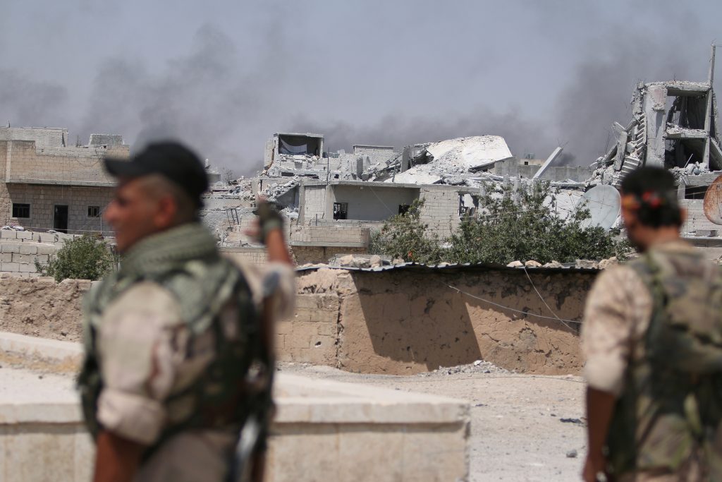 Syria Democratic Forces fighters look towards rising smoke from damaged buildings in Manbij in Aleppo Syria