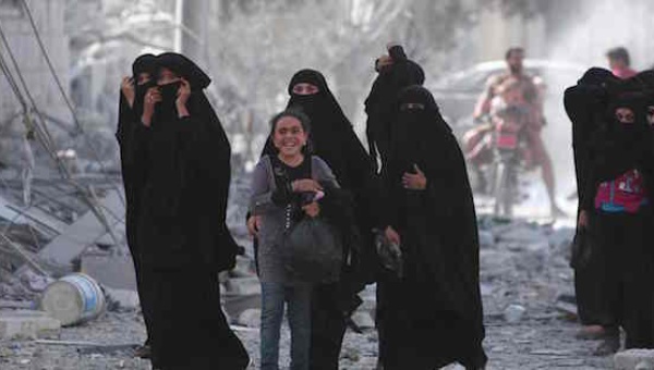 A girl walks with women who were evacuated by Syrian Democratic Forces fighters from the Islamic State group-controlled city of Manbij Syria