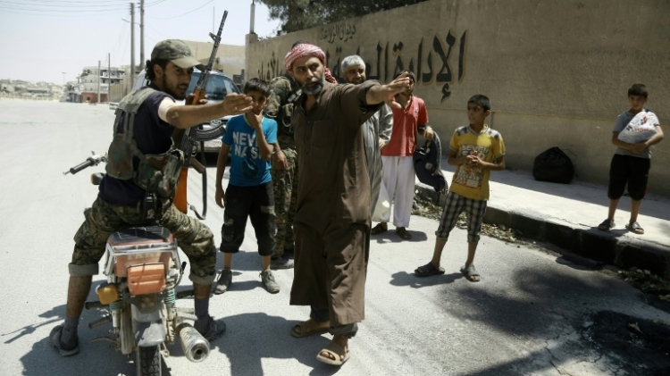 A member of the Syrian Democratic Forces indicates a safe street to civilians fleeing the zones controlled by the Islamic State group