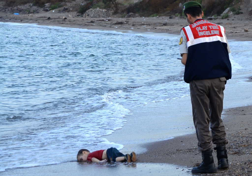 A Turkish police officer stands next to a migrant child's dead body off the shores in Bodrum southern Turkey