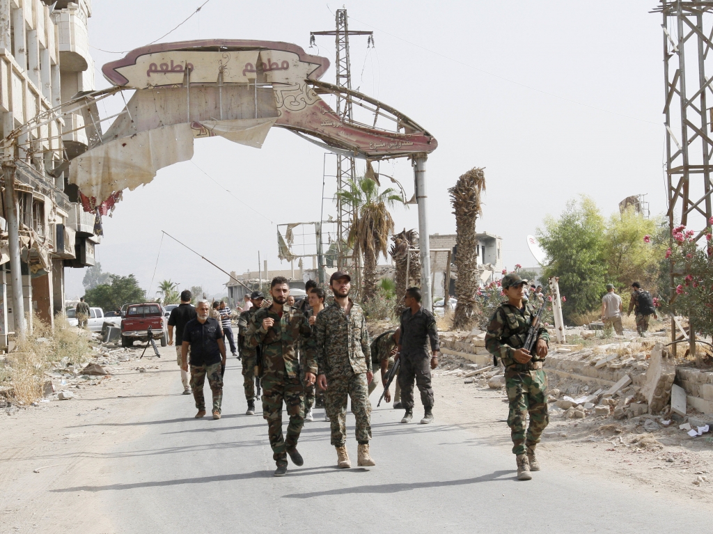 Syrian soldiers walk at the entrance of Daraya a besieged Damascus suburb on Friday.   AP