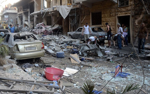 Syrians look at the damage in the Syriac Quarter of the regime-held area of Aleppo following a rocket attack by rebels