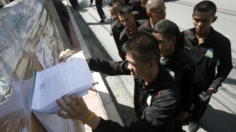 Thai soldiers line up to check their names before voting in a referendum on a new constitution at a polling station in Bangkok Thailand