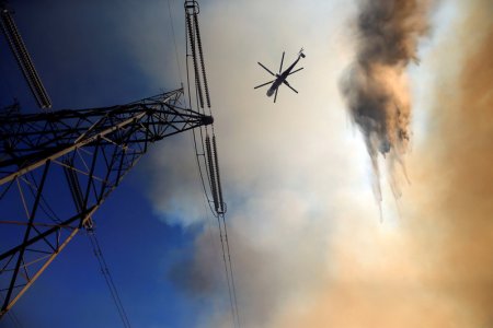 A firefighting helicopter makes a drop close to power lines to protect homes during the Blue Cut fire in San Bernardino County California