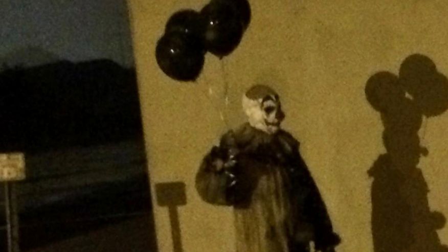 Mysterious creepy clown carrying black balloons spotted walking around city at night