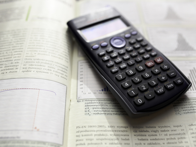 This stock image shows a scientific calculator and a math textbook