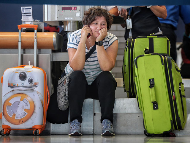 Cary Hart waits at the Delta ticket counter while trying to straighten out her travel plans to Moscow. Hart was routed through Detroit but that flight along with hundreds of others were canceled after a power outage in Atlanta and the