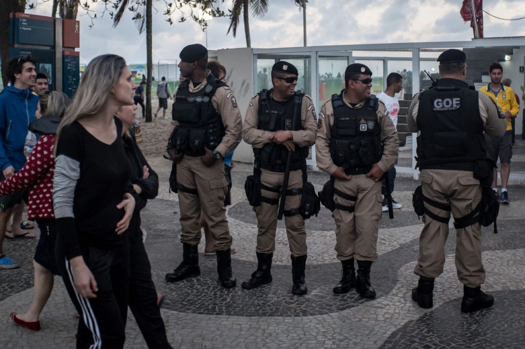 Tourists pass by as police stand guard along Copacabana Beach