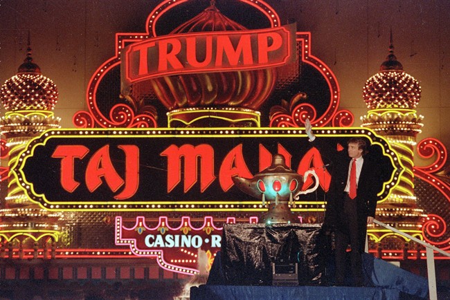 Donald Trump stands next to a genie lamp as the lights of his Trump Taj Mahal Casino Resort light up the evening sky marking the grand opening of the venture in Atlantic City N.J