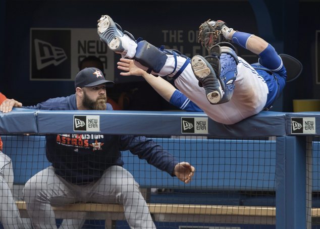 Toronto Blue Jays catcher Russell Martin goes over the rail into the Houston Astros dugout to catch a foul ball by Alex Bregman during the seventh inning