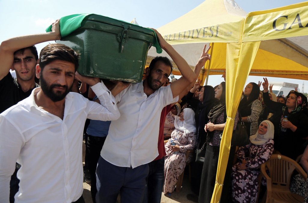 People carry a victim's coffin as they attend funeral services for dozens of people killed in last night's bomb attack targeting an outdoor wedding party in Gaziantep southeastern Turkey Sunday Aug. 21 2016. The suicide attacker was an Islam