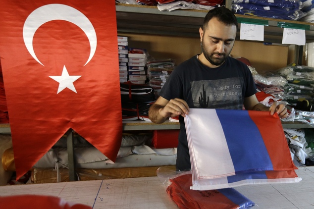 An employee of a flag-making factory folds a Russian flag as a Turkish flag adorns the display at left in Istanbul Tuesday Aug. 9 2016. The Factory prod