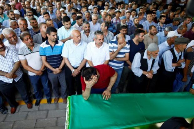 A family member of a victim of a suicide bombing at a wedding celebration mourn over a coffin during a funeral ceremony in the southern Turkish city of Gaziantep Turkey