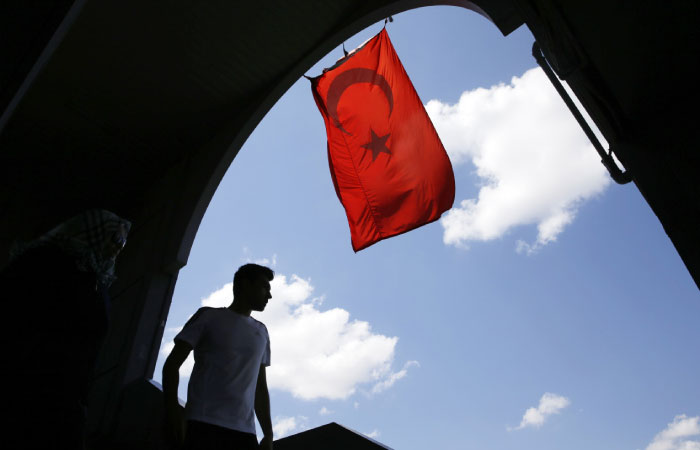 A pedestrian passes under a Turkish flag in Istanbul. Turkish authorities have prepared an official request for the temporary arrest of United States-based cleric Fethullah Gulen over his alleged involvement in the coup attempt on July 15. — AP