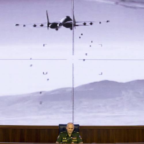 Rudskoi of the Russian Military General Staff speaks to the media as a video released by the Russian Defense Ministry shows a Russian warplane unloads its weapons over target on screen at a Russian Defense Ministry building in Mos