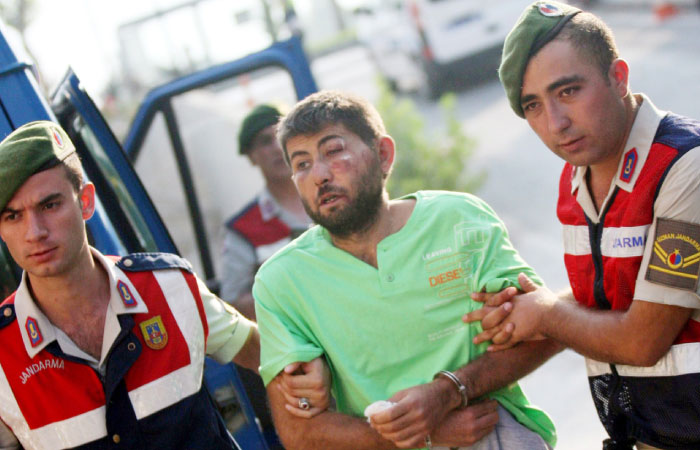 Turkish gendarmeries escort one of the 11 fugitive commandos who were involved in a bid to seize President Tayyip Erdogan during a failed coup attempt last month as he arrives at the police headquarters in Mugla Turkey on Monday. — Reuters