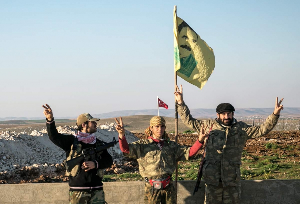 Syrian Kurdish militia members of the YPG make a V-sign next to a drawing of Abdullah Ocalan jailed Kurdish rebel leader in Esme village in Aleppo province Syria