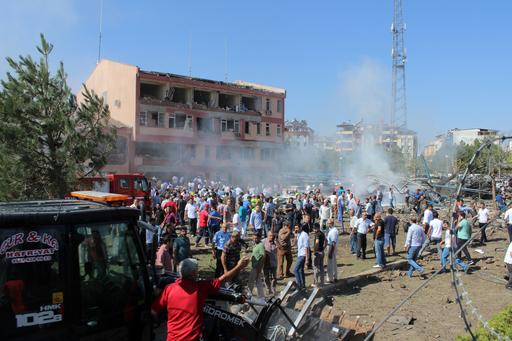 Turkish authorities and local residents stand outside a damaged building after an explosion in Elazig eastern Turkey on Thursday Aug. 18 2016. Two car bombings targeted police stations in Turkey killing a number of people and wounding hundreds offi