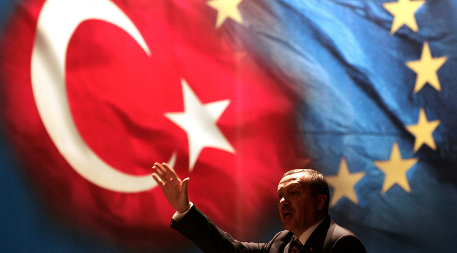 Turkish Prime Minister Tayyip Erdogan gestures under Turkish and EU flags in Istanbul