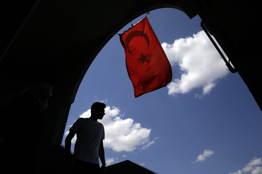 A pedestrian passes under a Turkish flag in Istanbul Sunday Aug. 14 2016. Turkish authorities have prepared an official request for the temporary arrest of United States-based Islamic cleric Fethullah Gulen over his alleged involvement in the coup atte