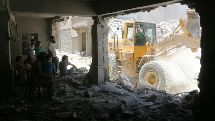 Syrians shelter in a damaged building as civil defence workers sift through debris looking for survivors following reported air strikes