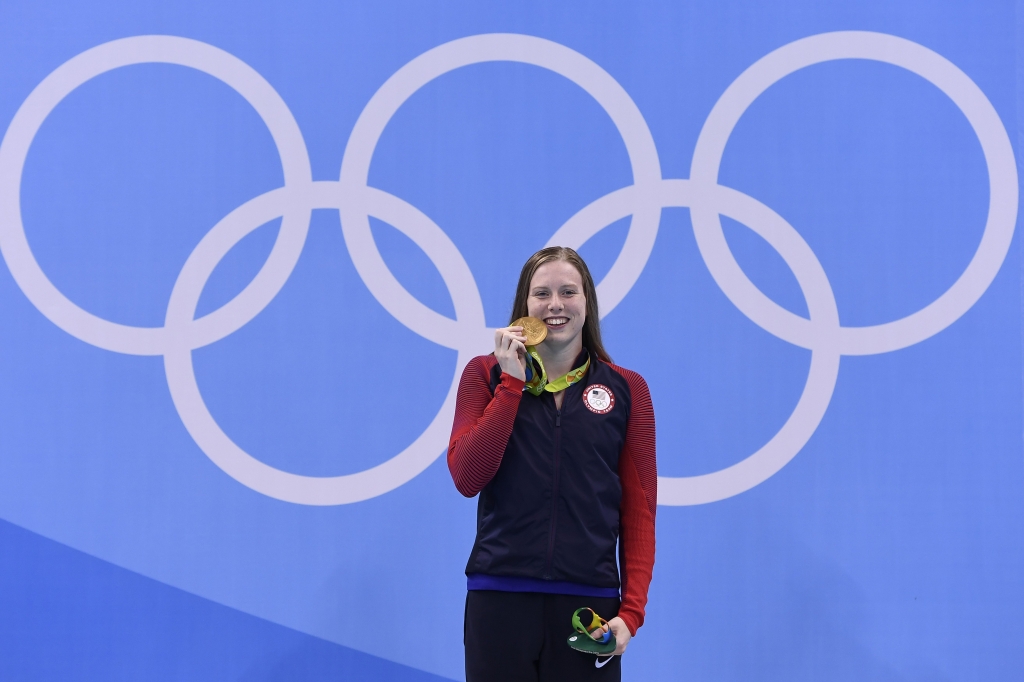 USA's Lilly King bites her gold medal on the podium after she won the Women's 100m Breaststroke Final during the swimming event at the Rio 2016 Olympic Games at the Olympic Aquatics Stadium in Rio de Janeiro