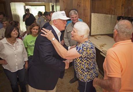 Republican presidential candidate Donald Trump center comforts flood victim Olive Gordon with her husband Jimmy right during tour of their flood damaged home in Denham Springs La. Friday Aug. 19 2016