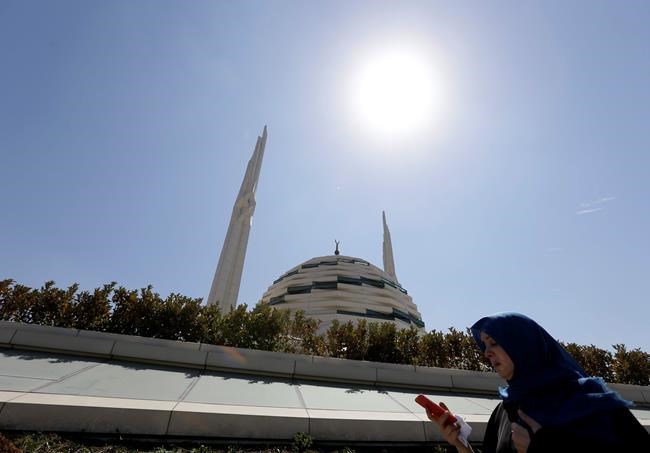 A woman checks her cell phone as she passes outside Marmara University Theological School mosque in Istanbul Friday Aug. 19 2016. Turkey accuses U.S.-based cleric Fethullah Gulen of masterminding the July 15th coup and has launched a massive crackdown