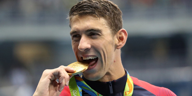 US Michael Phelps celebrates winning the men's 4x200-metre freestyle relay at the 2016 Rio Olympics by biting his medal