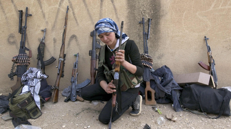 A Kurdish female fighter from Kurdish People's Protection Units checks her weapon near Ras al-Ain in the province of Hasakah after capturing it from Islamist rebels