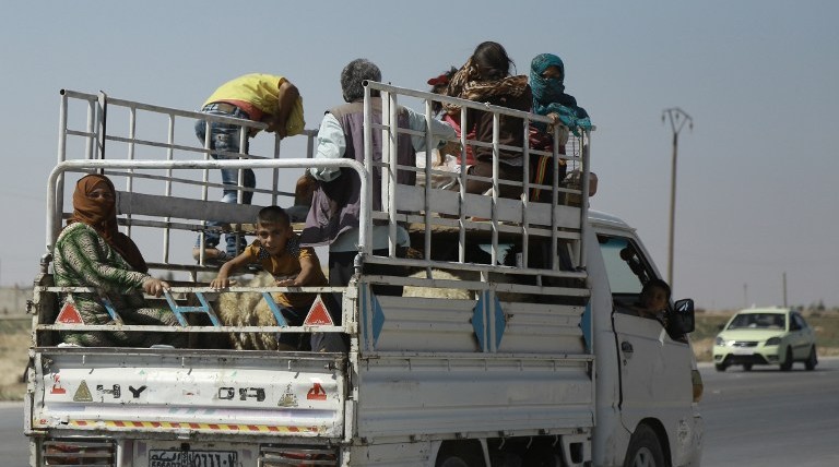 Syrian Kurdish civilians board a truck as they flee reported shelling in the northeastern governorate of Hasakah toward the city of Qameshli