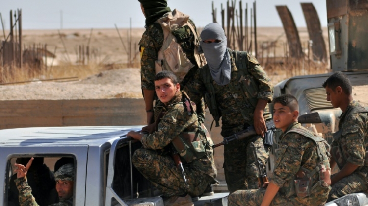 Fighters from the Kurdish People's Protection Units sit in the back of a vehicle in the al Zohour neighbourhood of the northeastern Syrian city of Hasakeh