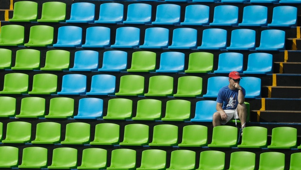 A fan sits surround by empty seats at the equestrian eventing dressage competition at the 2016 Summer Olympics in Rio de Janeiro Brazil Sunday Aug. 7 2016. | AP