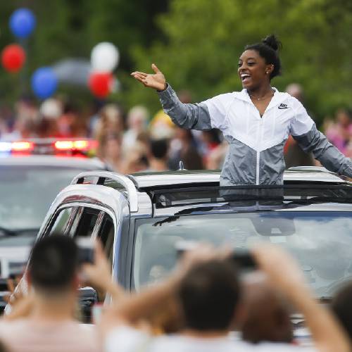 Biles waives to fans as she is welcomed home with a small parade along Rayford Road Wednesday Aug. 24 2016 in Spring Texas after winning four gold medals and a bronze at the Olympics in Rio de Janeiro. ( Michael Ciaglo  Houston