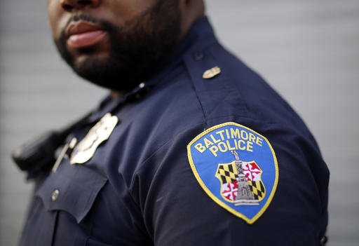 Baltimore Police Department Officer Jordan Distance stands on a street corner during a foot patrol in Baltimore. Baltimore police officers routinely discriminate against blacks repeatedly use excessive force and