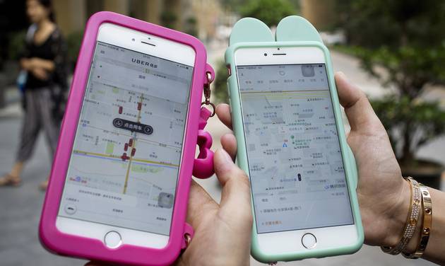 Women holding their smartphones show the ride-hailing apps Uber Technology Ltd. left and Didi Chuxing at a residential compound in Beijing Monday Aug. 1 2016. Uber Technology's main Chinese rival Didi Chuxing says it is acquiring the U.S. ride