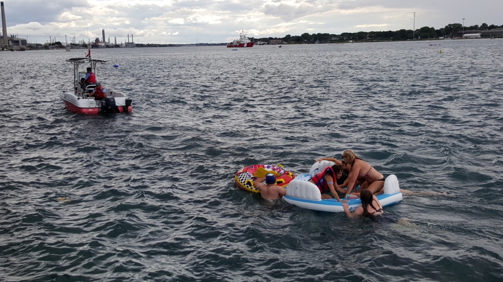 A Canadian Coast Guard ship tows floatation devices used by U.S. partiers to the Canadian side of the St. Clair River between Michigan and Ontario