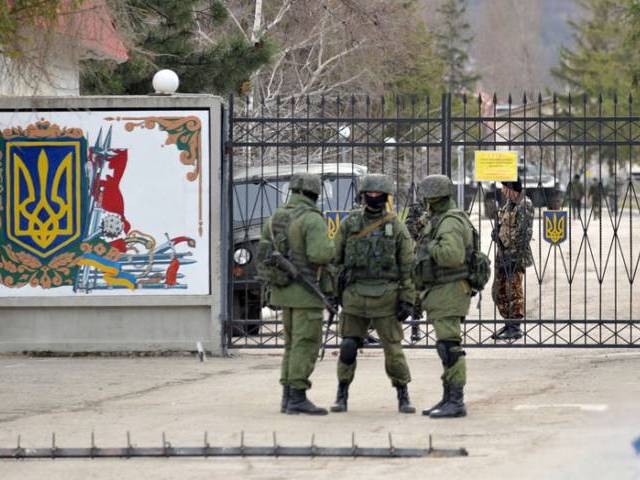 Ukrainian soldiers stand guard inside their base blocked by Russian troops in Perevalnoye near Simferopol