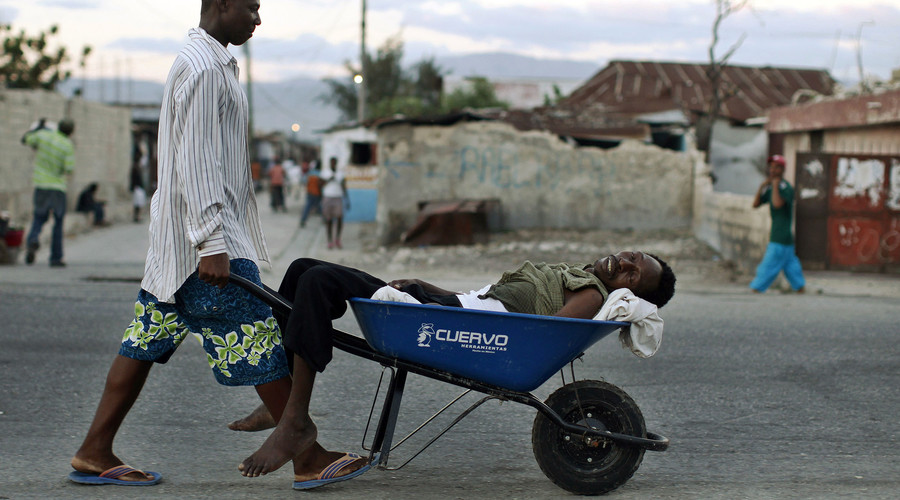 A Haitian with symptoms of cholera is transported in a wheelbarrow in the slums of Cite Soleil in Port-au Prince