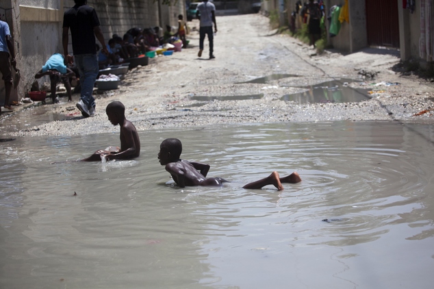 Young boys bathe in muddied water pooled in the middle of a street in Delmas a neighborhood of Port-au-Prince Haiti Friday Aug. 19 2016. Haiti is the