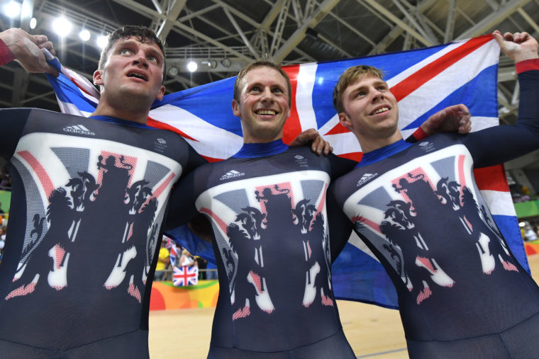 Britain's Callum Skinner Britain's Jason Kenny and Britain's Philip Hindes hold up a British flag as they celebrate after winning gold in the men's Team Sprint track cycling finals