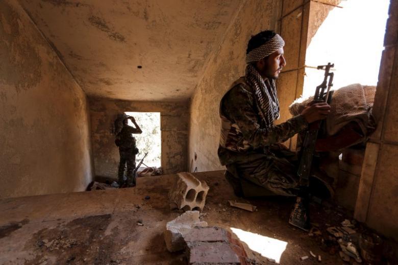 Protection Units fighters taking up positions inside a damaged building in al Vilat al-Homor neighborhood in Hasaka city as they monitor the movements of Islamic State fighters who are stationed in Ghwayran neighbor