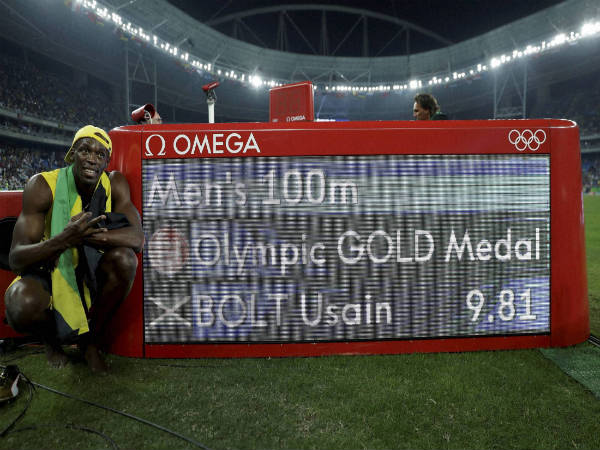 Usain Bolt poses beside the timing panel after winning the gold medal in the men's 100-meter final at the Rio Olympics 2016