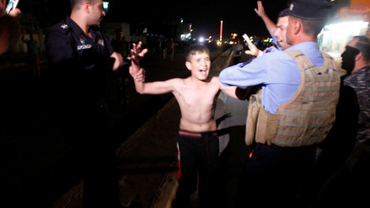 The boy looks visibly distressed as he is detained by security forces